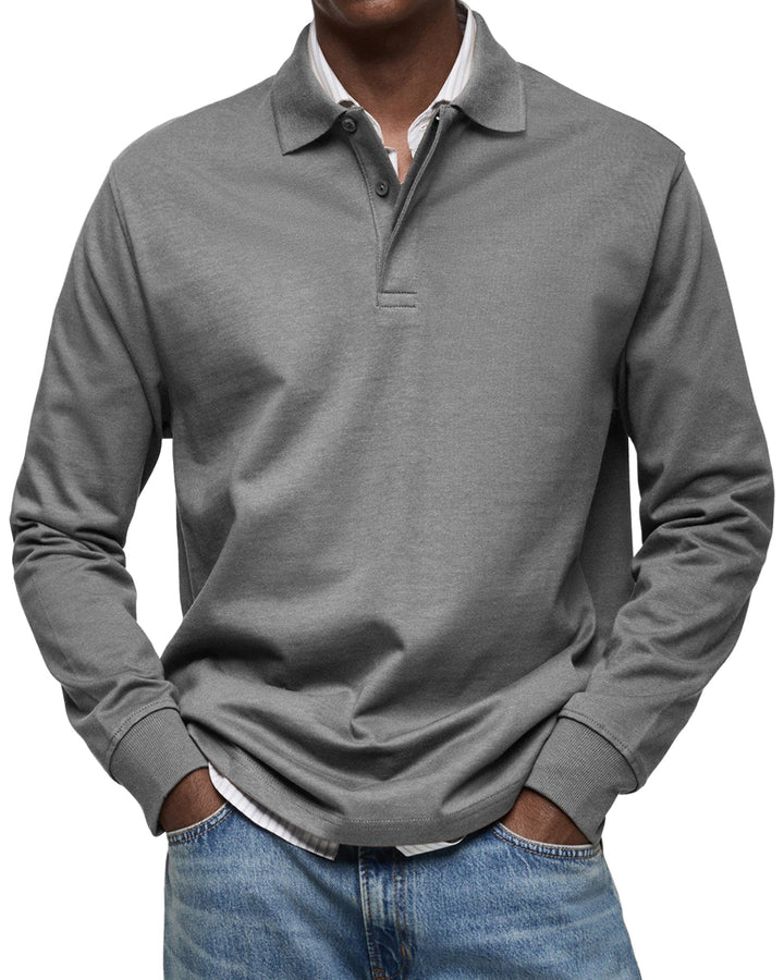 Polo à manches longues gris moyen porté par un homme, mains dans les poches, poignets côtelés, chemise rayée dessous et jean. 6