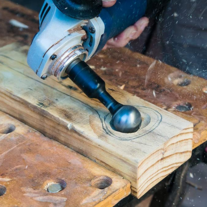 Outil sphérique monté sur une meuleuse d'angle creusant une cavité dans une planche, copeaux projetés 2