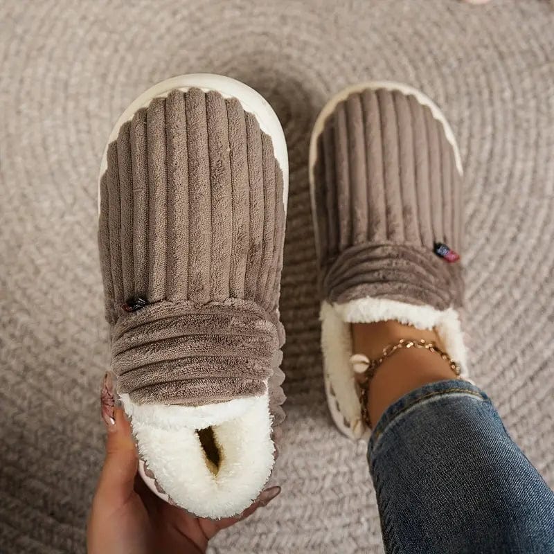 Chaussons marron côtelés vus de dessus sur un tapis, l'un tenu en main montrant la doublure, l'autre porté. 14