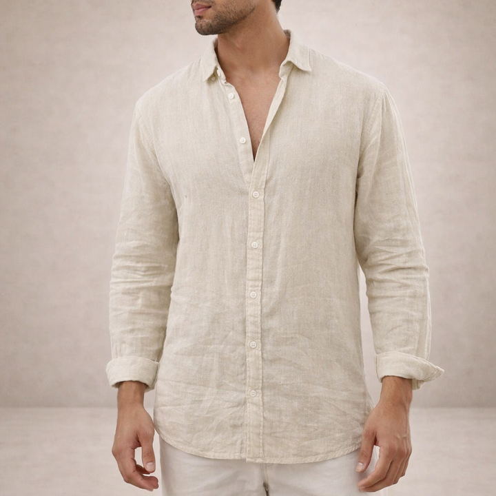 Chemise en lin beige clair portée de face, col ouvert, boutons nacrés et manches retroussées, avec un pantalon blanc. 6