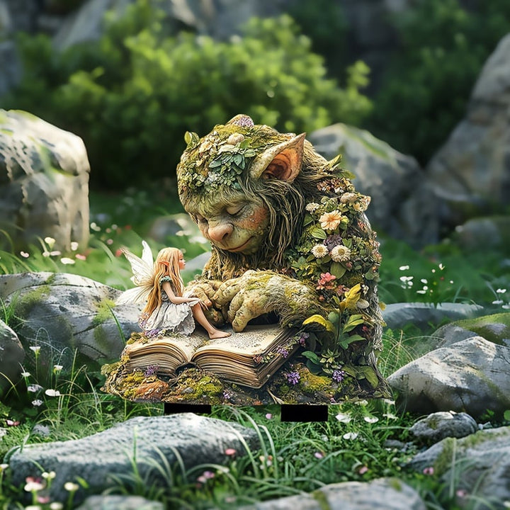 Tuteur du troll couvert de fleurs et de la fée sur un livre, posé dans l'herbe entre de gros rochers. 12