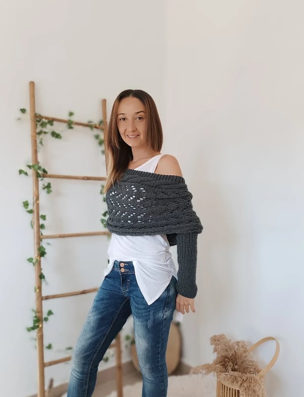 Châle gris foncé porté en trois quarts, une épaule dénudée, une manche tombant le long du bras, devant une échelle décorative. 4