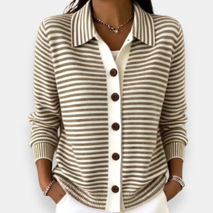 Gilet à rayures taupe et blanches porté par une femme, col chemise, cinq boutons marron sur bande blanche, mains dans les poches. 1