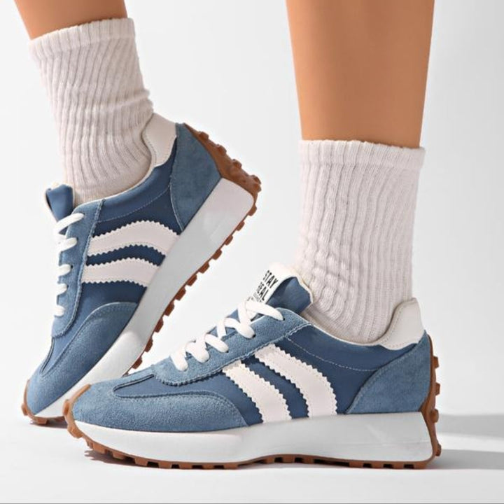Baskets bleues portées avec des chaussettes blanches côtelées, vue de profil montrant les bandes et la semelle 8