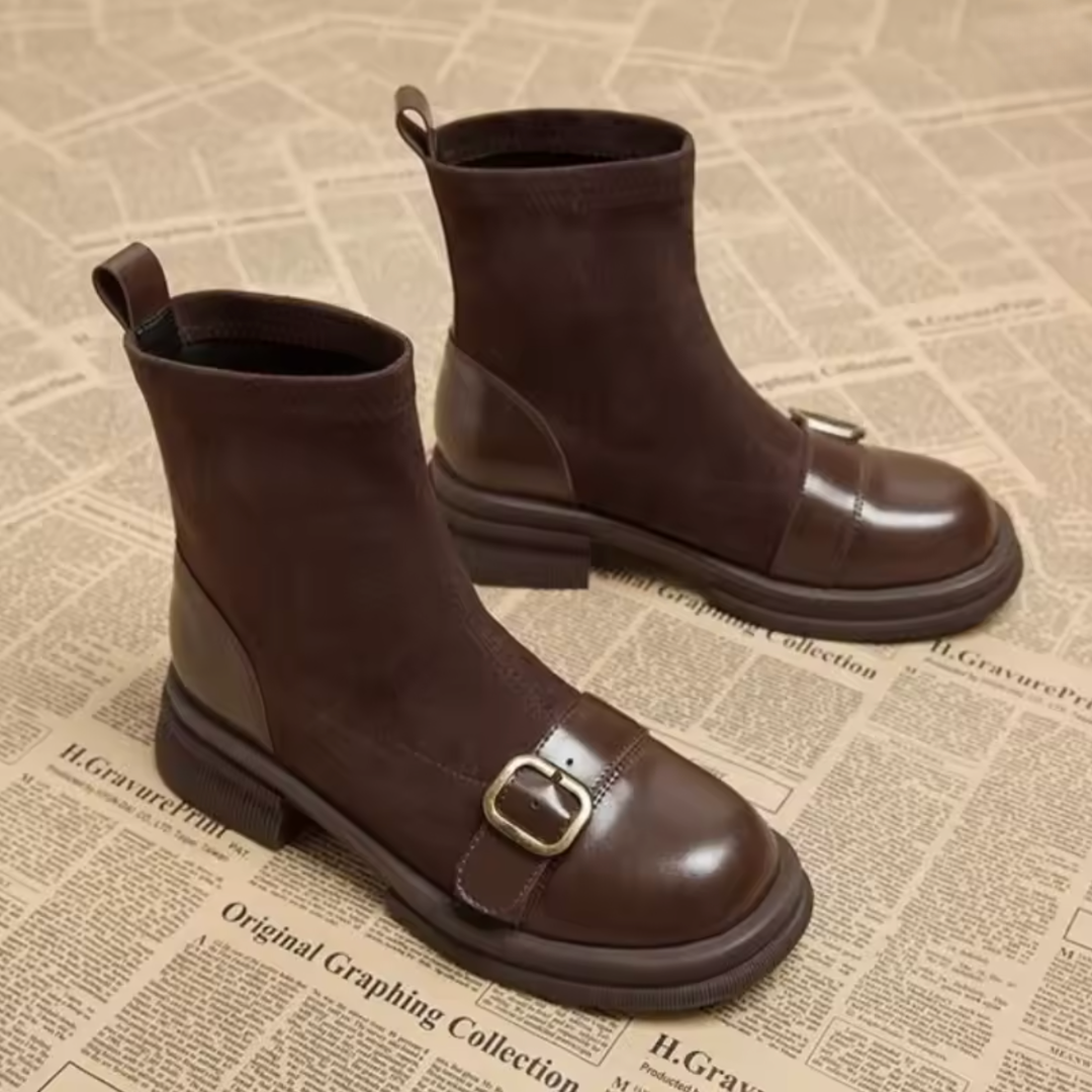 Paire de bottines marron posées sur un fond de papier journal, avec boucle dorée sur le bout arrondi en cuir. 3