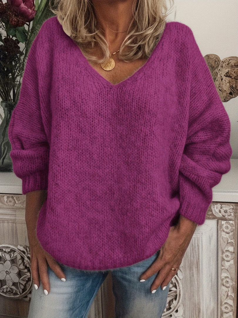 Pull violet fuchsia à col en V, maille douce et ample, porté mains sur les hanches avec un jean. 6