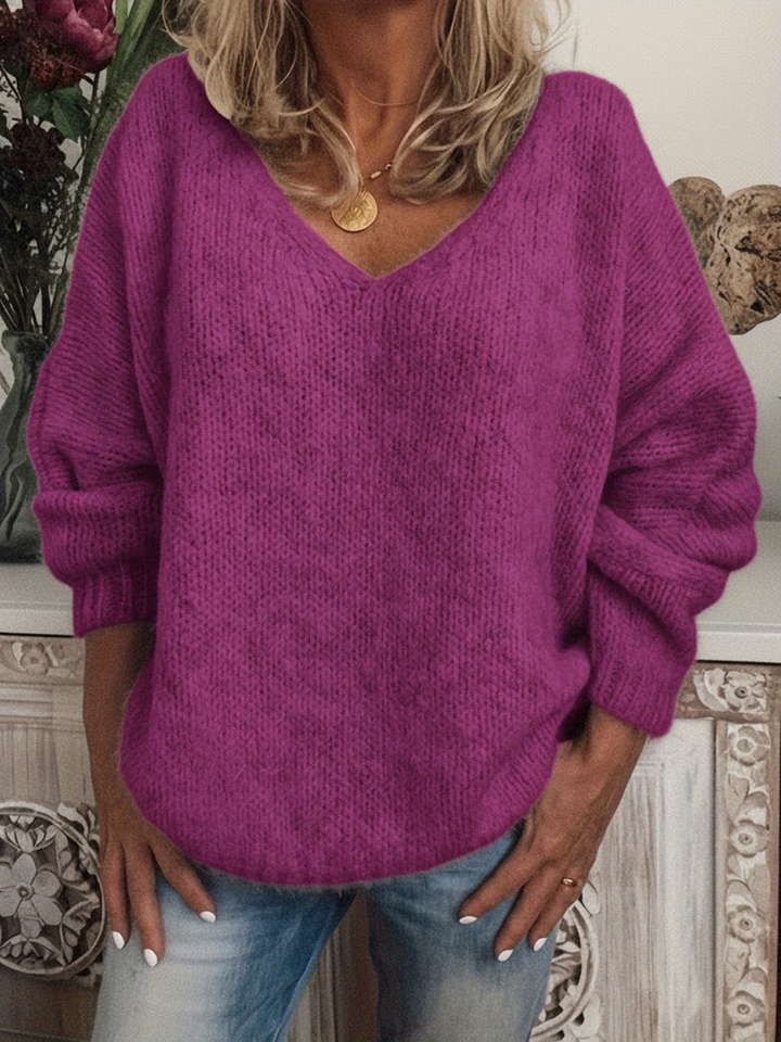 Pull violet fuchsia à col en V, maille douce et ample, porté mains sur les hanches avec un jean. 6