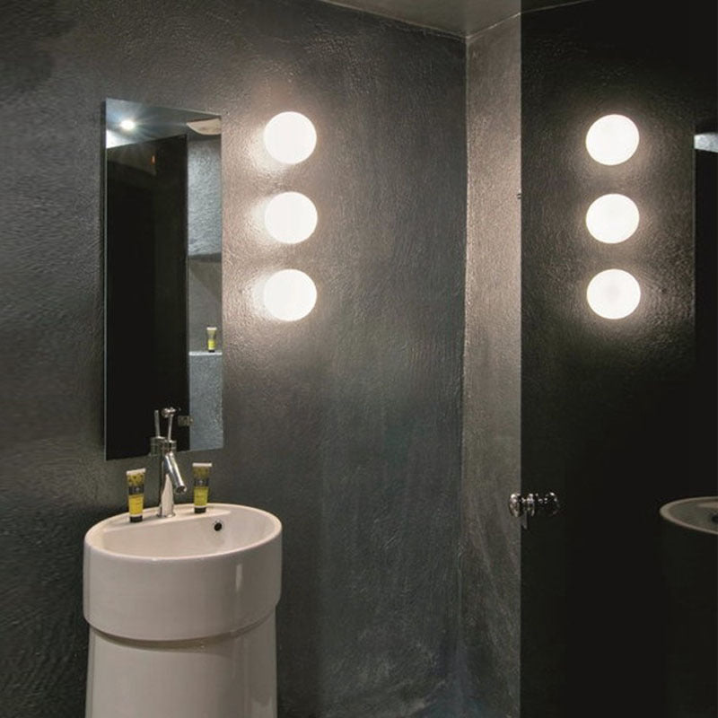 Trois sphères blanches superposées au mur d'une salle d'eau sombre, à côté d'un miroir et d'une vasque 11