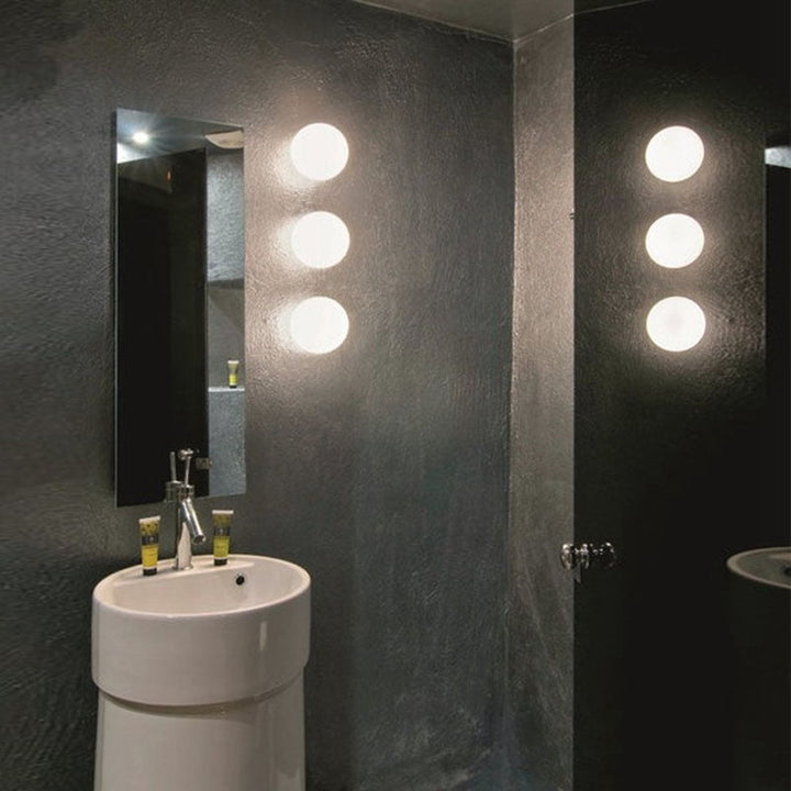Trois sphères blanches superposées au mur d'une salle d'eau sombre, à côté d'un miroir et d'une vasque 11