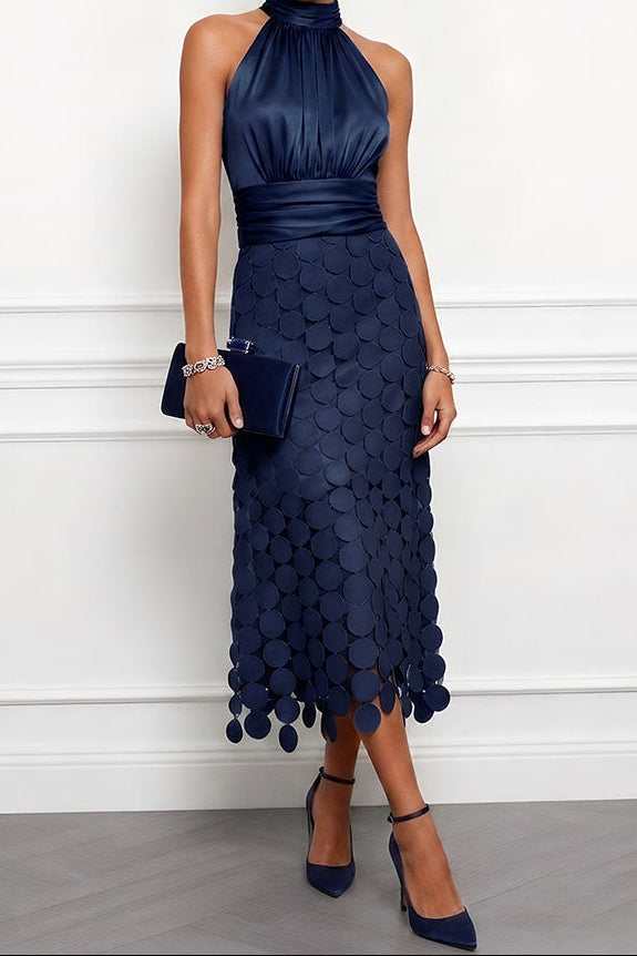 Robe midi bleu marine à col licou, corsage satiné et jupe de disques, portée avec une pochette et des escarpins assortis. 4