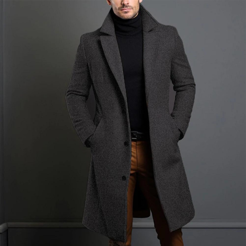 Manteau long en version gris anthracite chiné, porté par un homme en col roulé noir et pantalon marron. 3