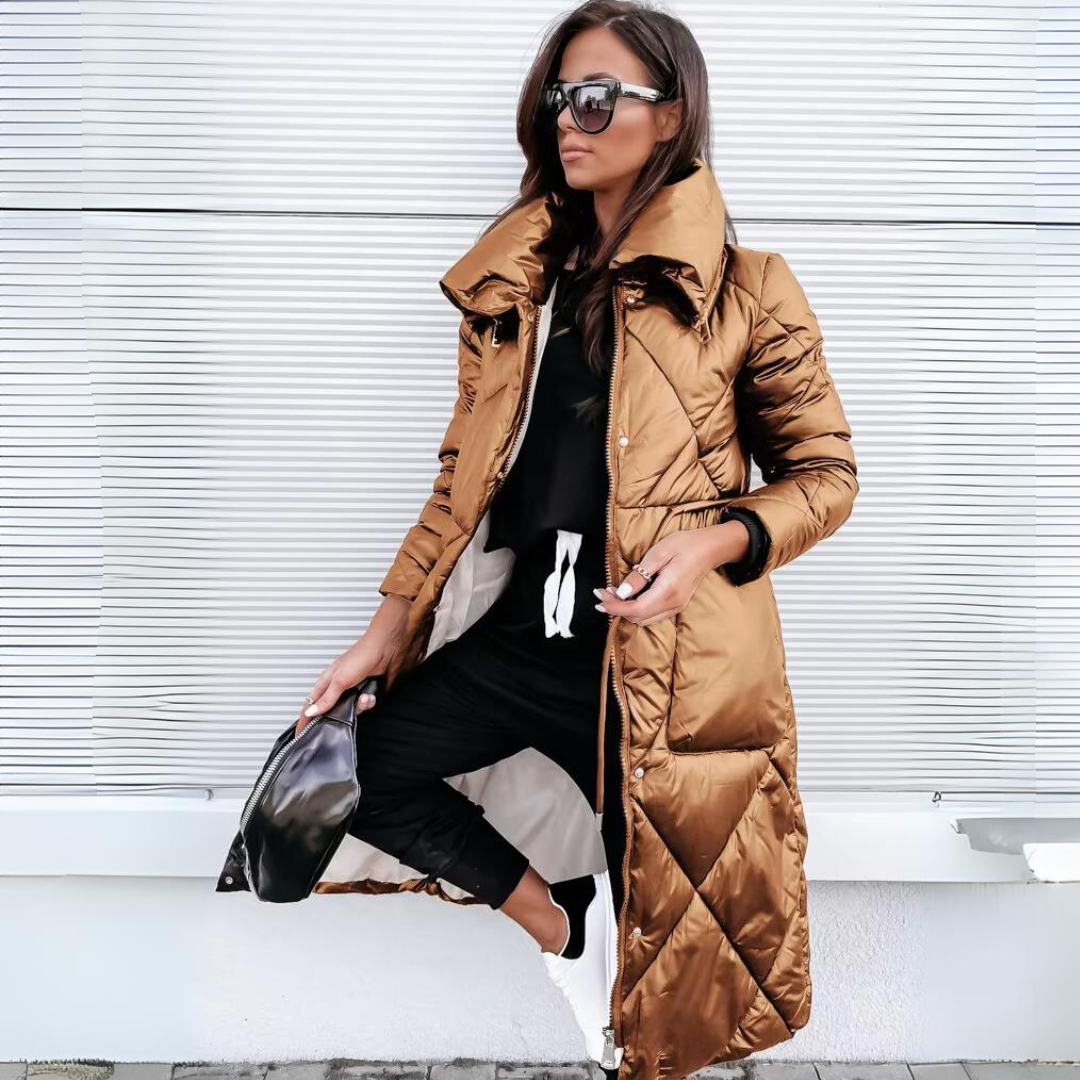 Même manteau matelassé long dans une teinte cuivrée métallisée, porté ouvert par une femme avec lunettes de soleil et sac noir. 2