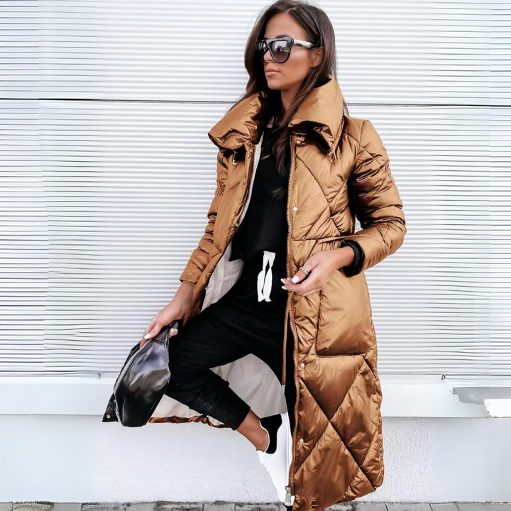 Même manteau matelassé long dans une teinte cuivrée métallisée, porté ouvert par une femme avec lunettes de soleil et sac noir. 2