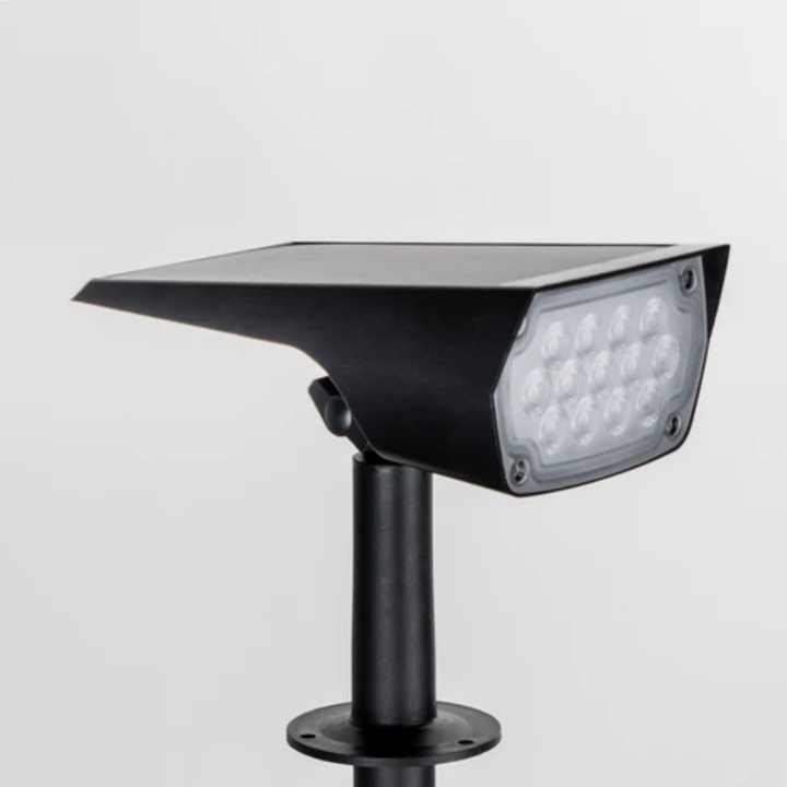 Gros plan sur la tête noire du projecteur avec son panneau solaire sur le dessus et la rangée de LED à l'avant, sur fond clair. 4