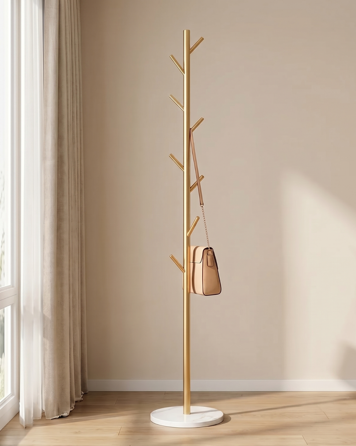 Version dorée du portant, avec socle rond blanc, un sac à main beige accroché et un rideau à côté. 4