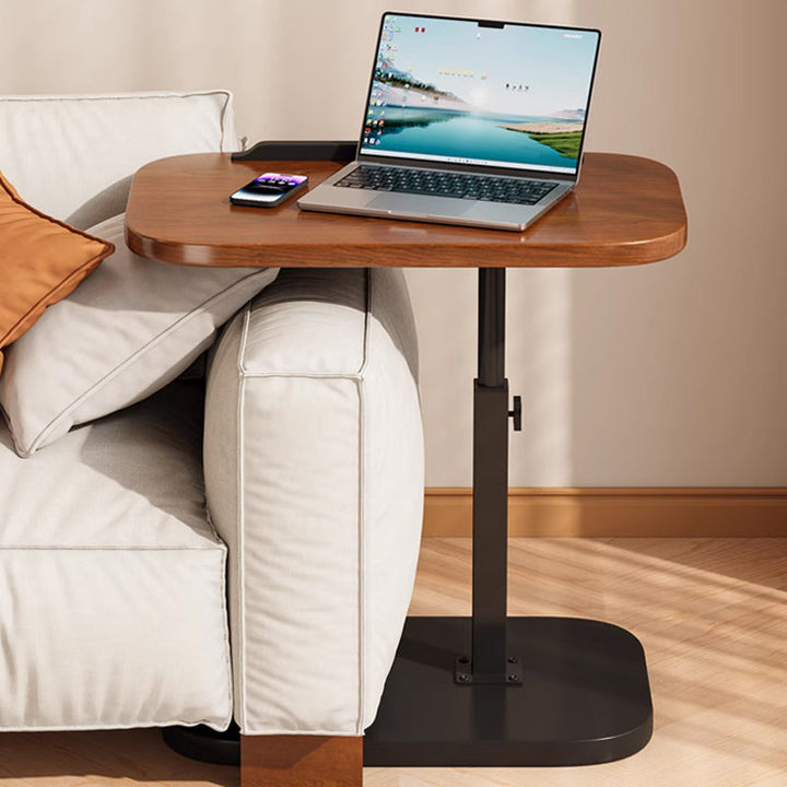 Plateau avancé au-dessus de l'accoudoir du canapé, avec ordinateur portable et téléphone, la base noire glissée sous l'assise. 11