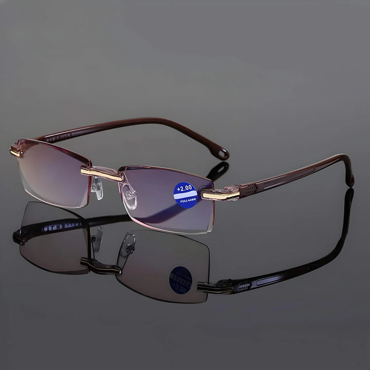 Lunettes sans monture à branches brunes et charnières dorées, posées sur une surface réfléchissante grise avec leur reflet. 7