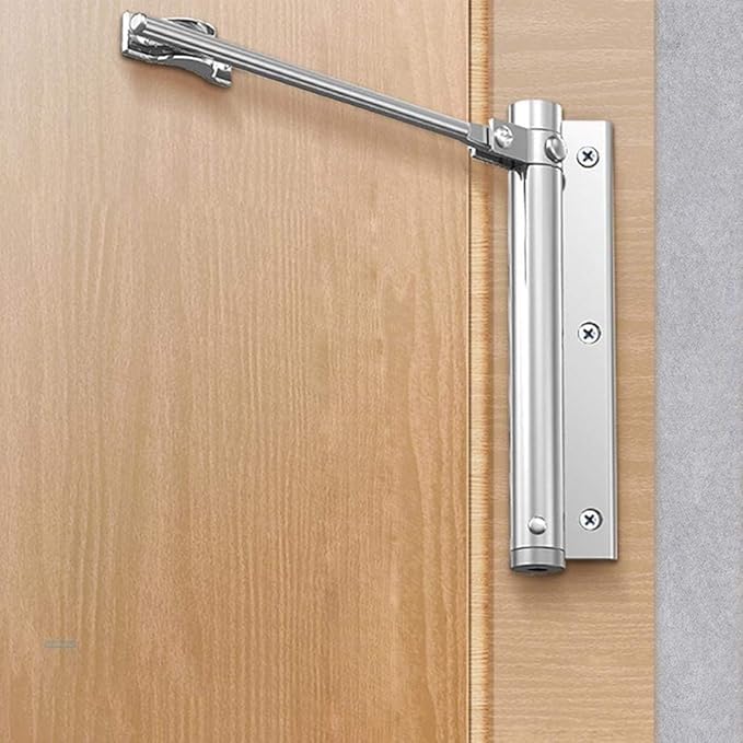 Ferme-porte argenté monté sur une porte en bois clair, bras déployé, vu de côté 2