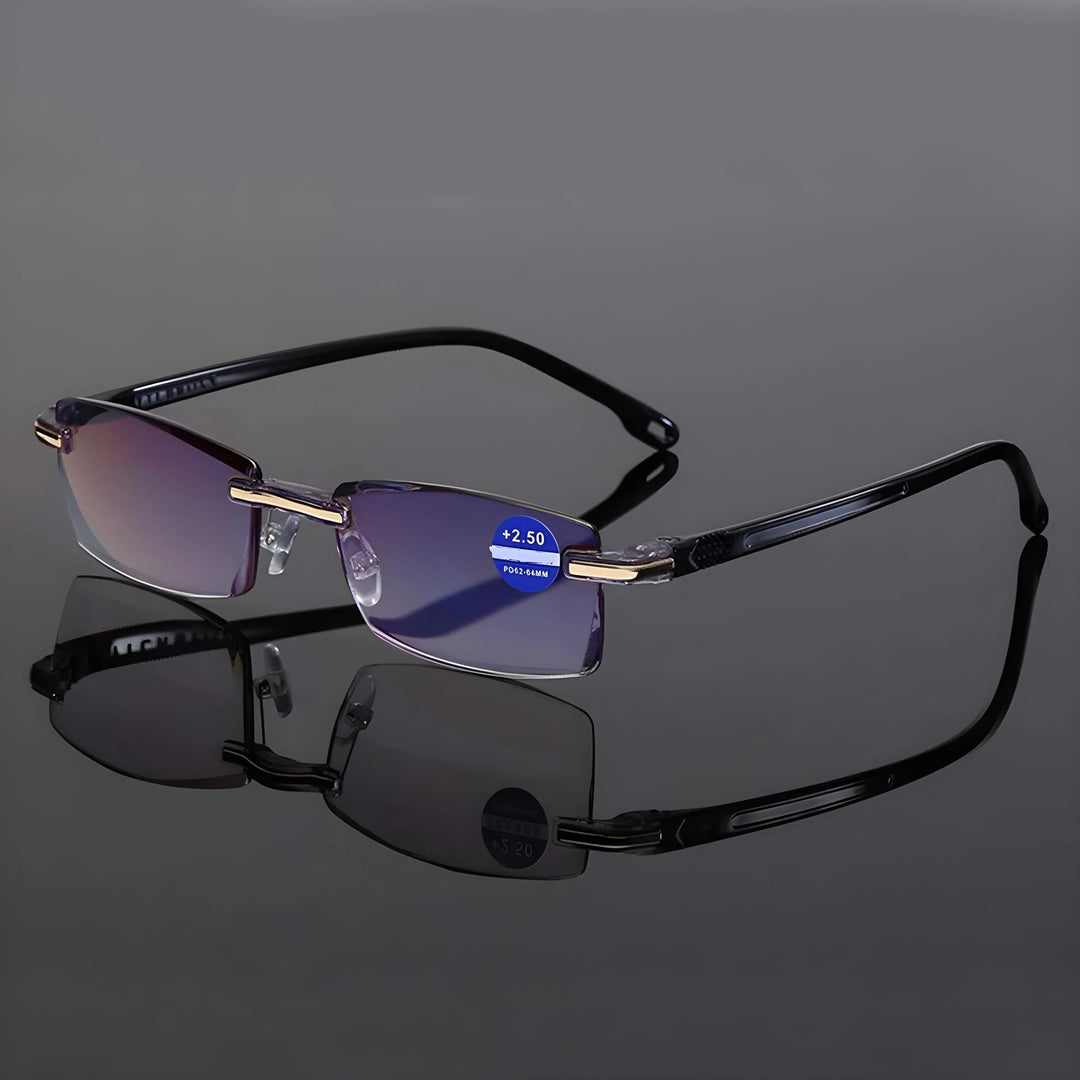 Lunettes sans monture à branches noires et charnières dorées, posées sur une surface réfléchissante grise avec leur reflet. 6