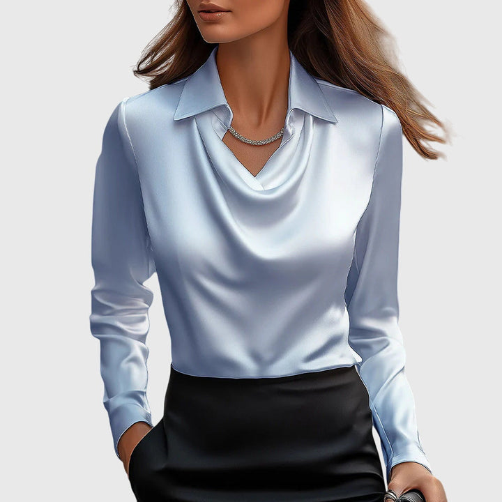 Blouse en satin bleu ciel à col drapé et manches longues, portée avec une jupe noire et un collier de strass. 4