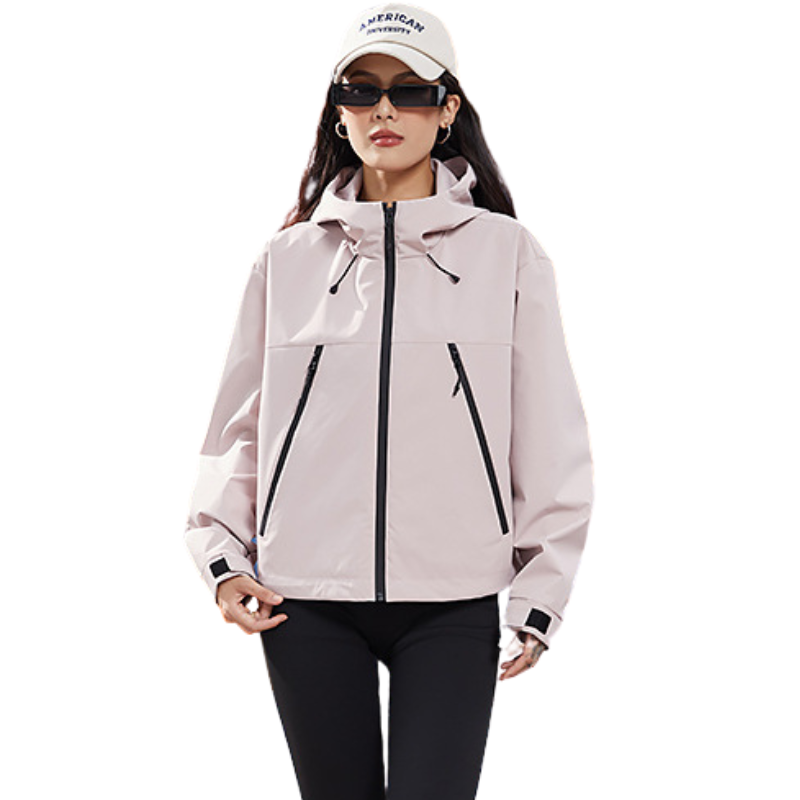 Veste courte rose pâle à capuche portée avec casquette blanche et lunettes fines, vue de face, poignets à bande Velcro noire. 9