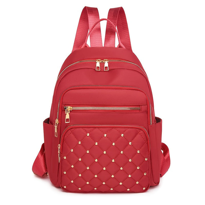 Sac à dos rouge vu de face, poche avant matelassée avec clous dorés 16