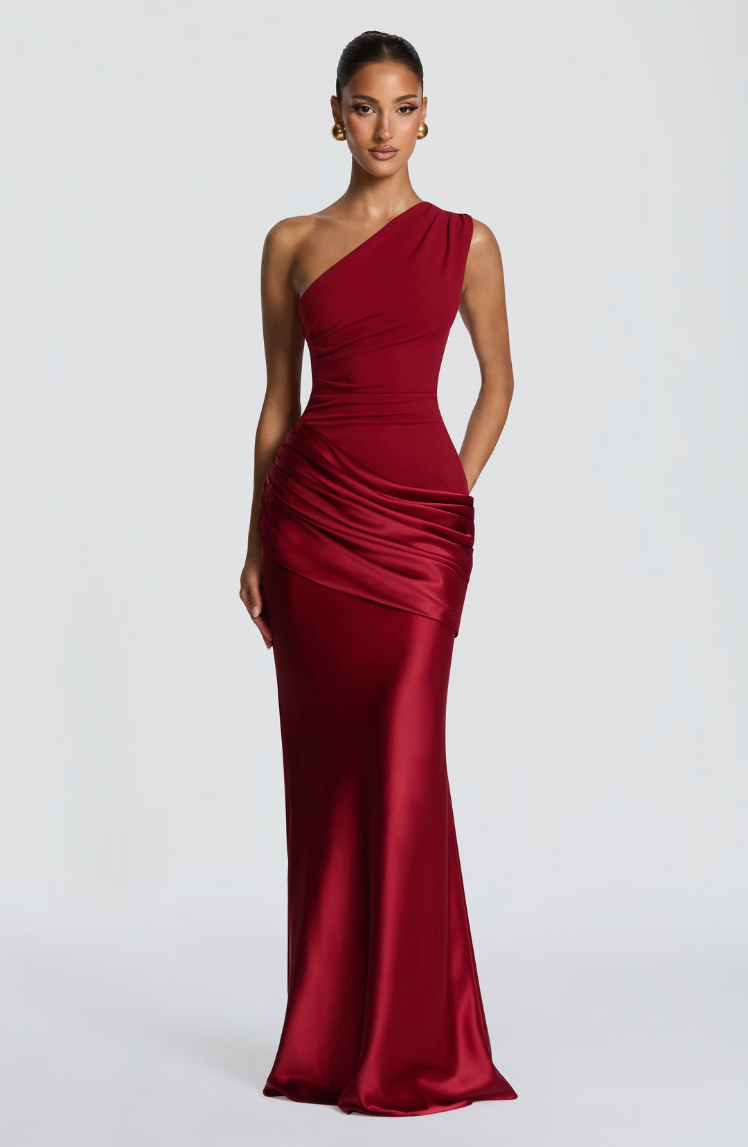 Robe longue rouge bordeaux portée de face, mannequin mains le long du corps, satin brillant et haut asymétrique. 17