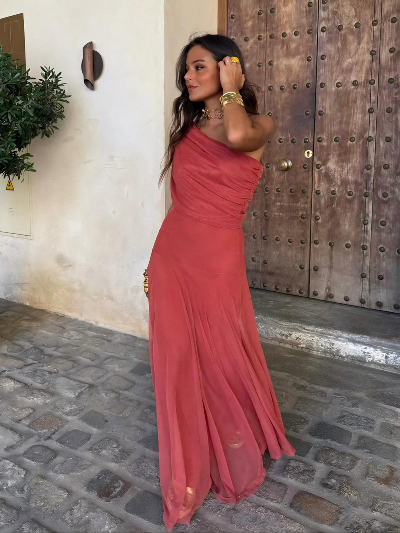 Robe longue corail à une épaule, portée de trois quarts devant une grande porte en bois 4