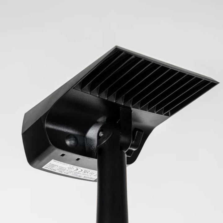 Vue de dessous de la tête du projecteur noir, montrant les ailettes, l'articulation de réglage, la vis et l'étiquette technique collée sous le boîtier. 5