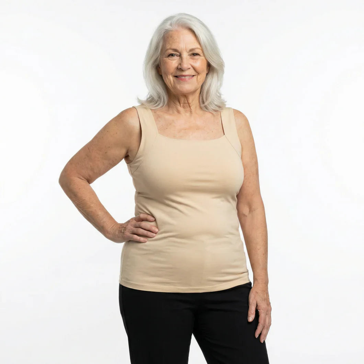 Femme aux cheveux gris souriante, main sur la hanche, portant le débardeur beige à encolure carrée avec un pantalon noir. 5