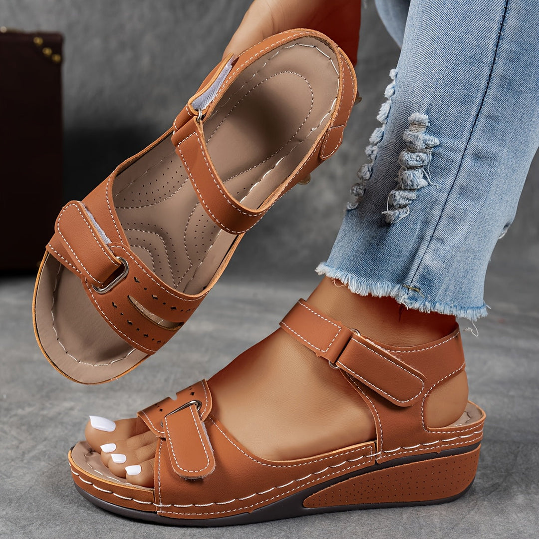 Sandales compensées marron caramel à brides auto-agrippantes et surpiqûres claires, portées avec un jean déchiré, l'autre sandale montrant son intérieur confort 5