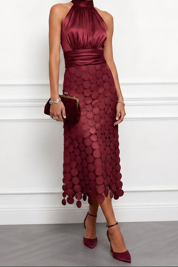 Robe midi bordeaux à col licou, corsage en satin et jupe de disques, portée avec une pochette à fermoir doré et des escarpins. 5