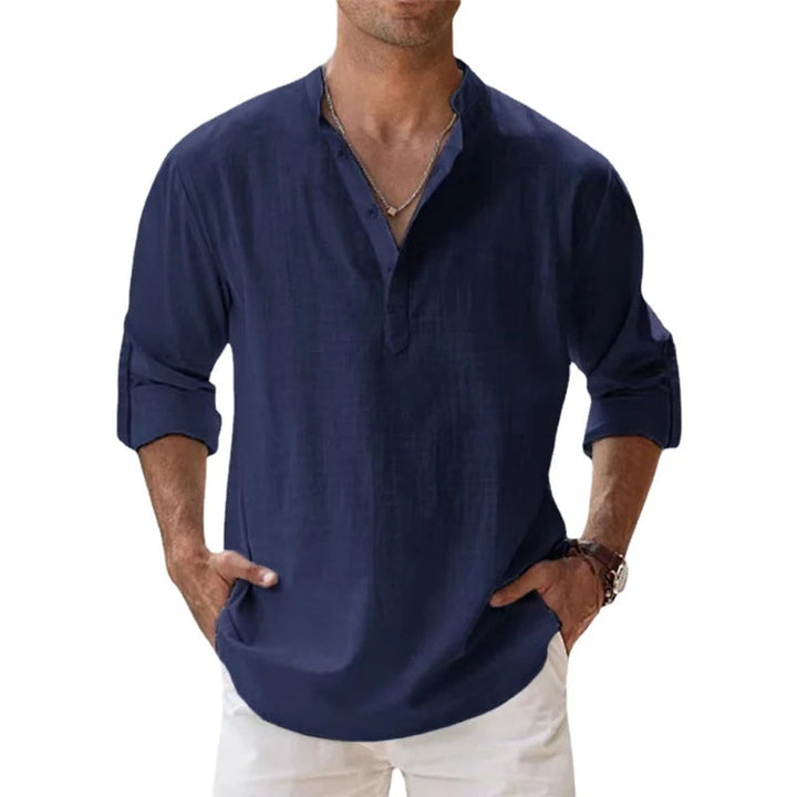 Homme portant la chemise Henley bleu marine, manches retroussées, mains dans les poches d'un pantalon blanc, vue de face. 5