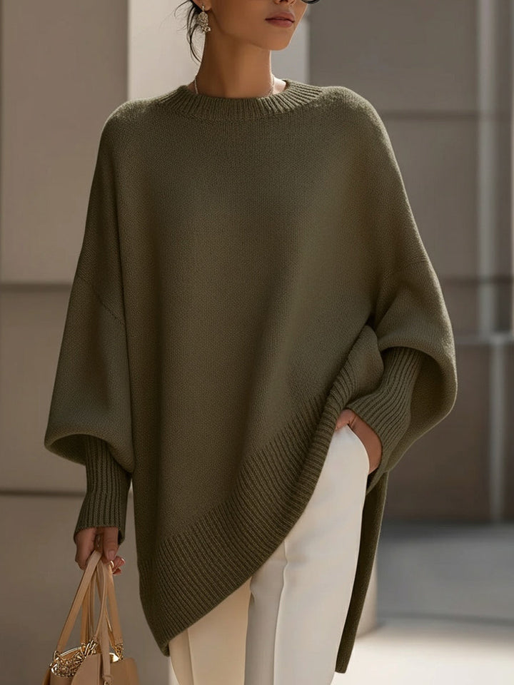 Poncho vert olive porté de face, manches amples à poignets côtelés, pantalon blanc 8