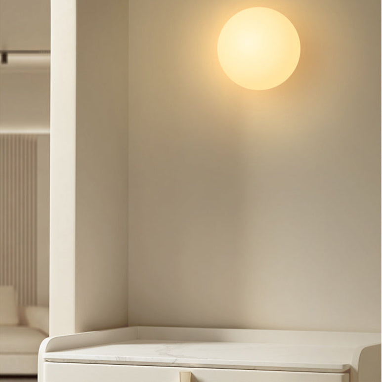 Sphère lumineuse murale à la lueur chaude, au-dessus d'une commode blanche au plateau en marbre 3