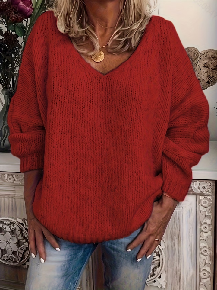 Pull rouge en grosse maille à col en V, manches longues à poignets côtelés, porté avec un jean. 5