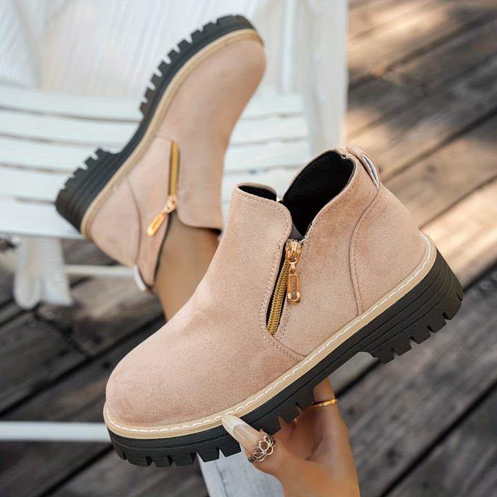Bottines rose poudré en daim, zip doré latéral et semelle noire crantée à surpiqûres blanches, portées sur du bois. 5