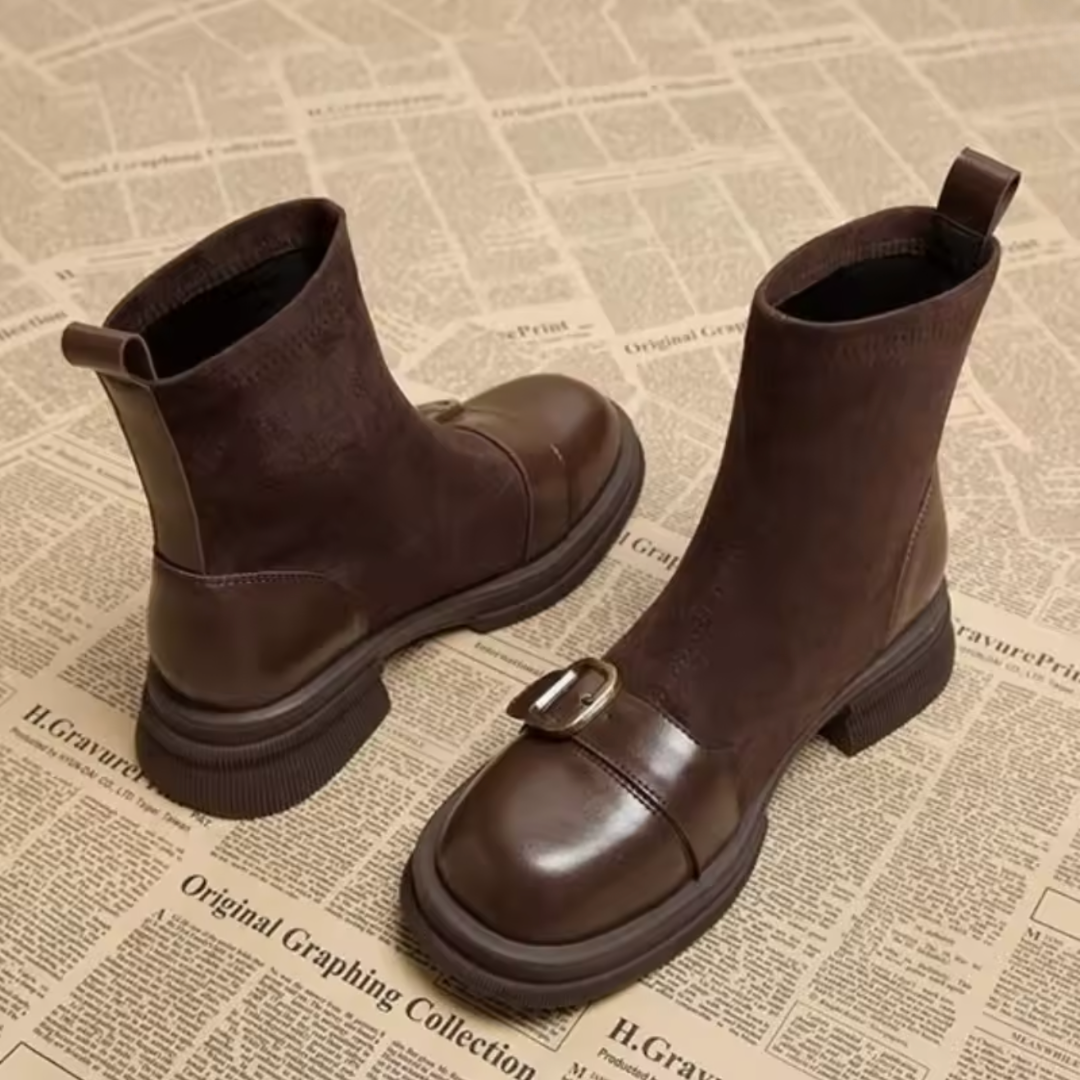 Bottines marron vues en trois quarts, tige en daim, bout en cuir brillant avec boucle métallique et talon bloc épais. 2