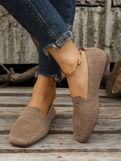 Jambes croisées portant la paire marron en maille perforée, avec un bracelet de cheville doré, sur un plancher en bois. 6