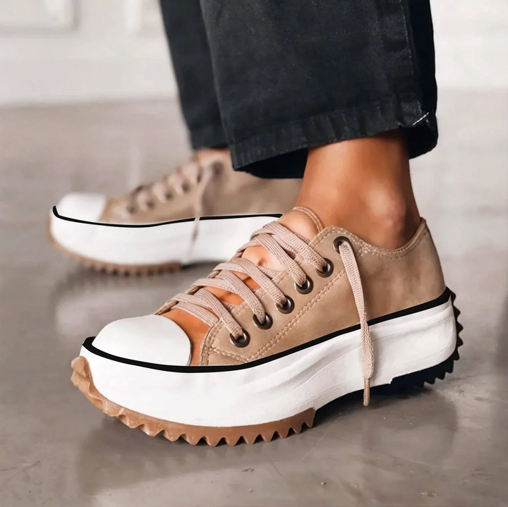 Baskets à lacets beige portées avec un pantalon noir, semelle plateforme blanche crantée et bout renforcé arrondi, vue de trois quarts 1
