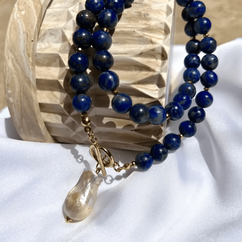 Collier enroulé sur un support en bois sculpté, fermoir à bascule et perle baroque visibles 7
