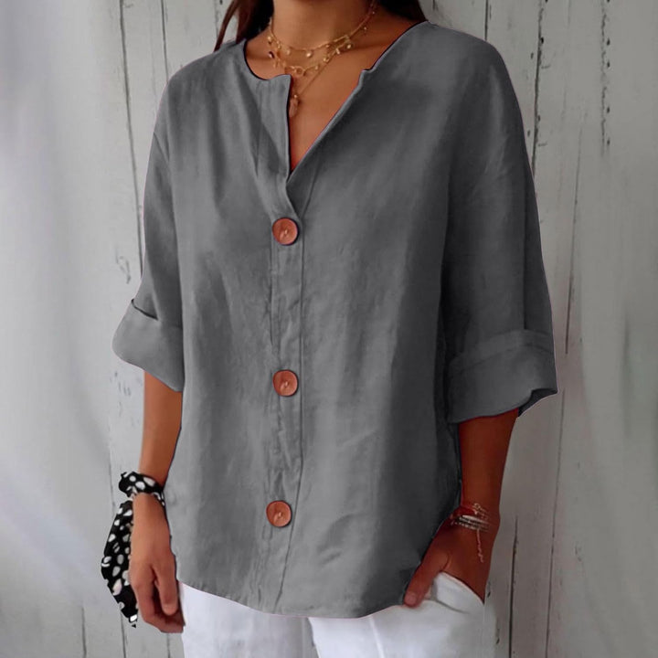 Même blouse en gris anthracite, portée avec un pantalon blanc et un chouchou à pois noir et blanc au poignet. 4