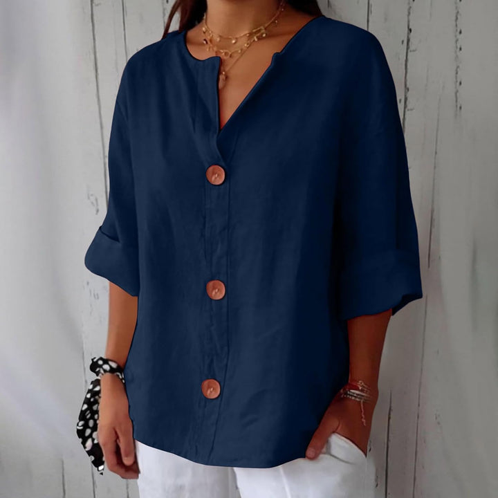 Même blouse boutonnée en bleu marine foncé, portée avec un pantalon blanc, manches retroussées et trois boutons en bois. 2