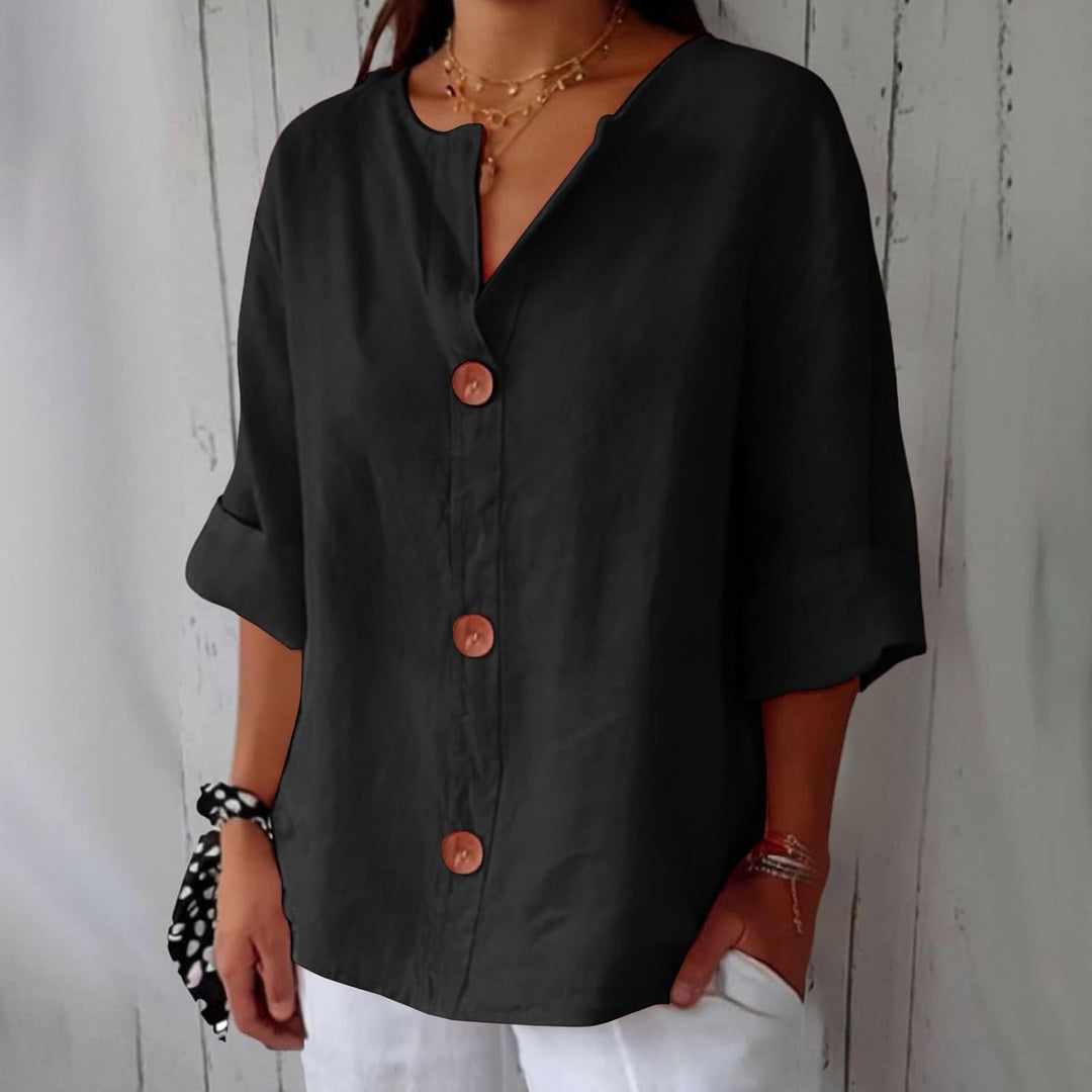 Même blouse en noir, portée avec un pantalon blanc, trois boutons en bois marron bien visibles sur la patte de boutonnage. 11