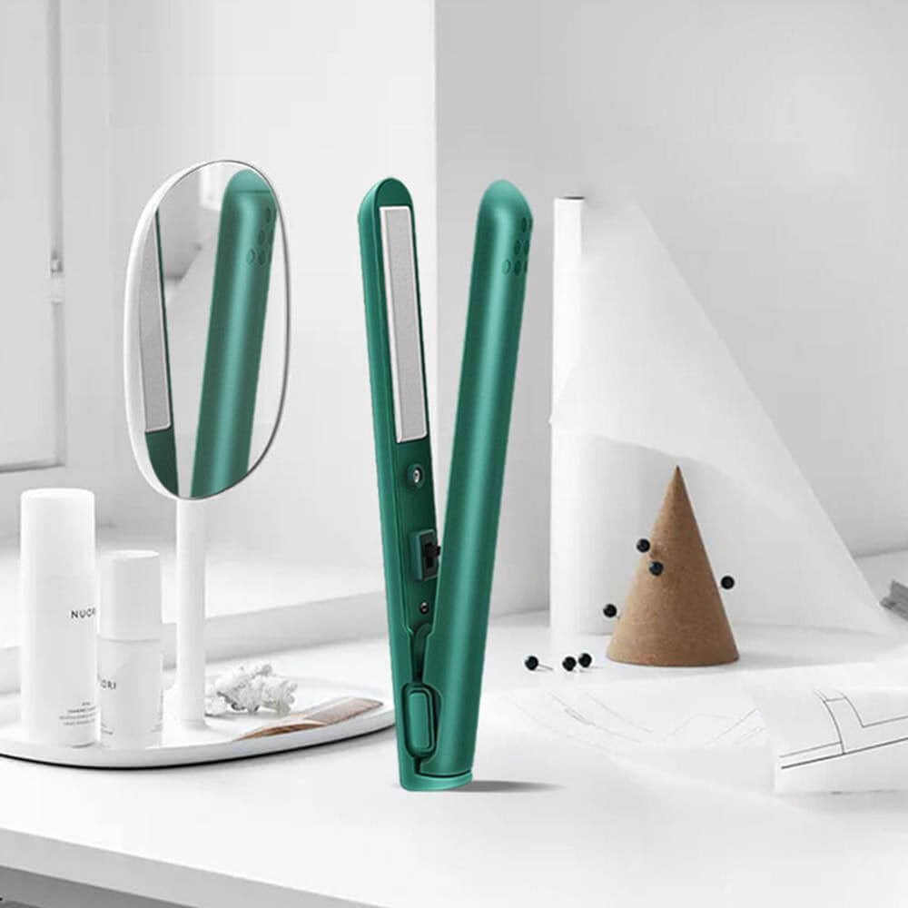 Lisseur vert ouvert posé sur une coiffeuse blanche, à côté d'un miroir ovale, de flacons et d'un cône décoratif. 2