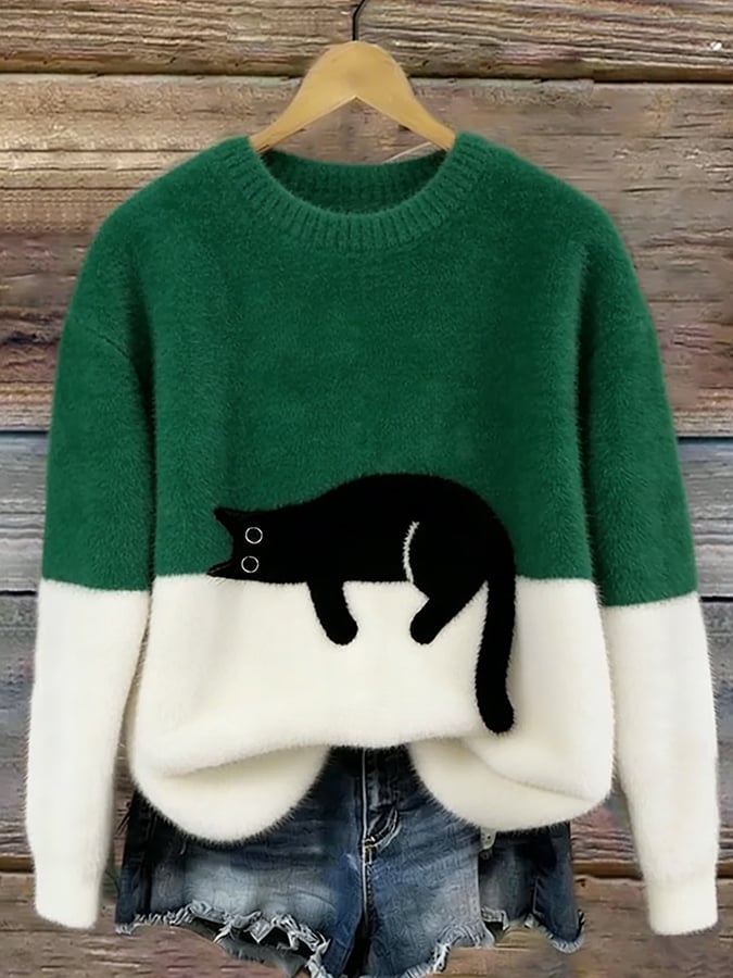 Version vert foncé et blanche du pull au chat noir étendu, présentée sur un cintre contre un mur en bois. 5