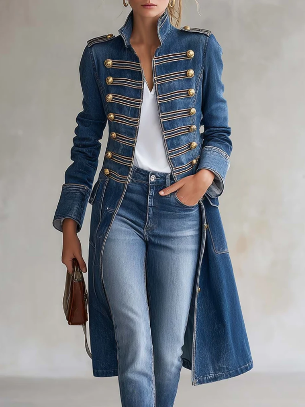 Manteau en denim bleu porté par une femme, boutons dorés et galons sur le devant, main dans la poche, sac marron. 1