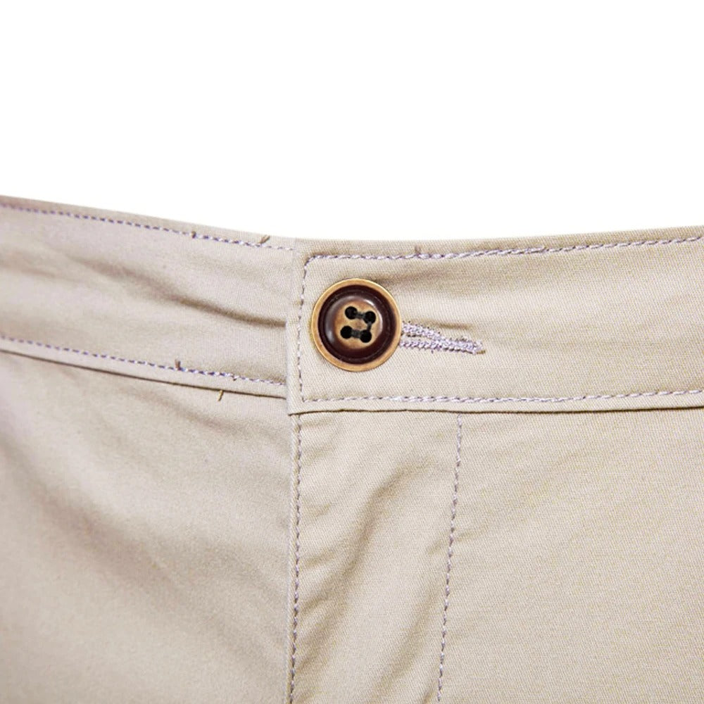 Gros plan sur le bouton marron à quatre trous et la boutonnière à la taille du short beige. 5