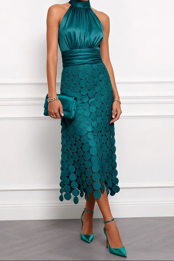Robe midi vert émeraude à col licou, corsage satiné et jupe de disques, portée avec une pochette et des escarpins assortis. 6