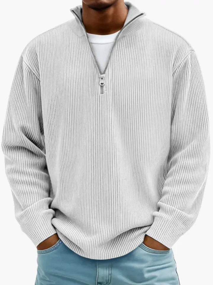 Homme portant le pull côtelé à col zippé en gris très clair, mains dans les poches d'un jean bleu clair. 6